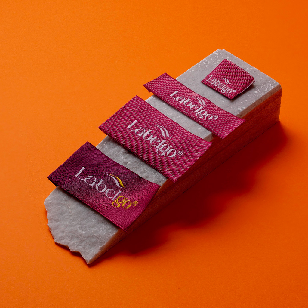 Bordeauxrote gewebte Satin-Etiketten mit glänzendem Finish auf Orange.