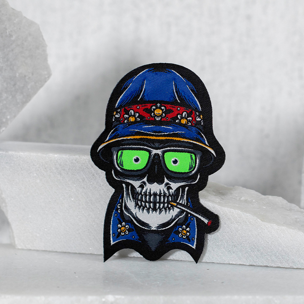 Gestickter Totenkopf Aufnäher mit blauem Hut und Brille.